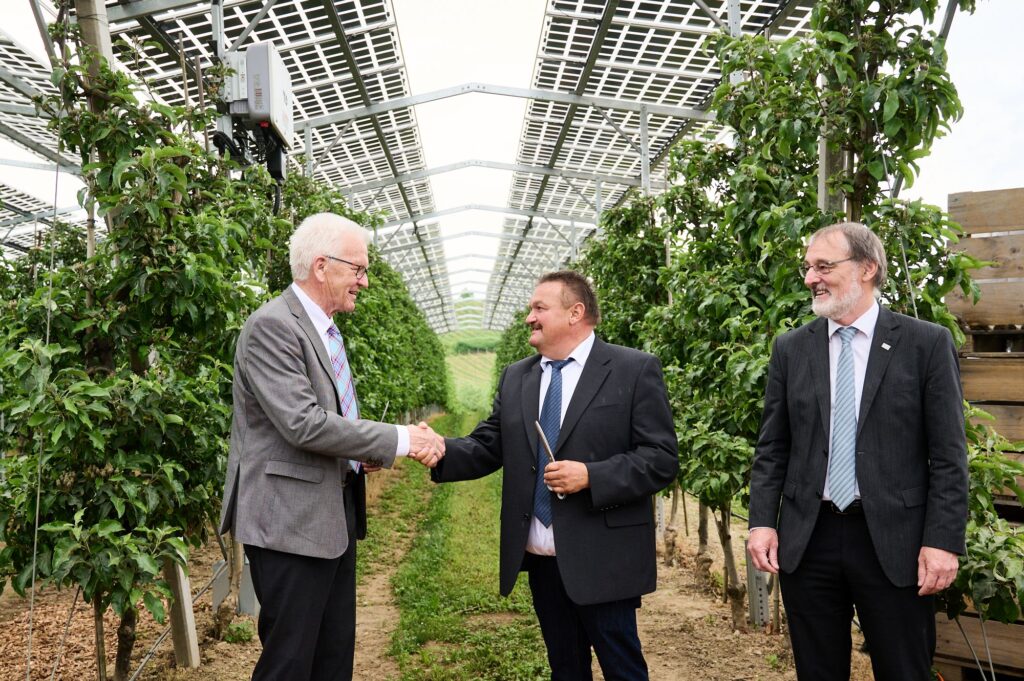 Il primo ministro del Baden-Württemberg Winfried Kretschmann, l&#39;agricoltore Hubert Bernhard e il prof. Andreas Bett, direttore dell&#39;Istituto Fraunhofer per i sistemi di energia solare, hanno inaugurato l&#39;impianto fotovoltaico agricolo a Kressbronn.